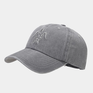 Detail of vintage washed gray baseball cap featuring fine turtle embroidery on front