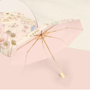 Detail of pink floral umbrella with gold metal ribs and smooth wooden handle