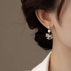 Gold plated horse pearl earrings with zircon inlay worn by model in a side view