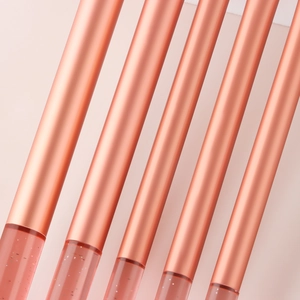 Close-up of makeup brushes with rose gold metal handles and pink liquid glitter details