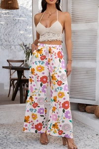 Détail de pantalon large à fleurs bohème et haut licou au crochet à franges assorti