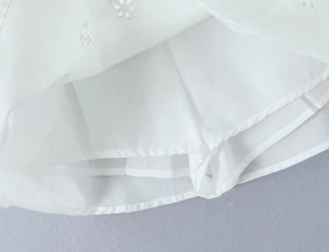 Détail de la jupe en dentelle blanche montrant la doublure et la broderie ajourée