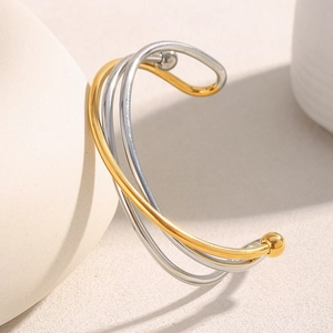 Vue détaillée d'un bracelet jonc croisé à trois couches en acier inoxydable doré et argenté