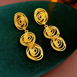 Detailed view of vintage gold spiral drop earrings on dark green velvet surface