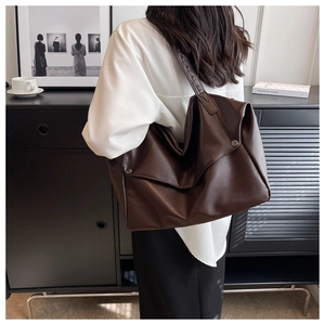 Close-up of brown textured leather tote bag featuring elegant silver side button details
