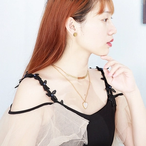 Detail of double-layer gold necklace and heart earrings with white shell pendants