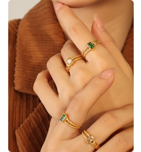 Detailed view of gold twist rings with emerald and clear rectangle zircon stones