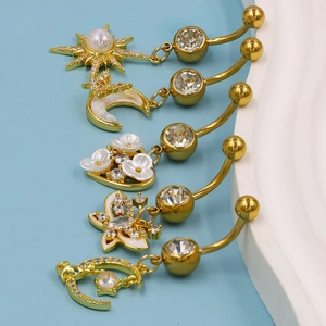 Detailansicht von fünf goldenen Bauchnabelpiercings mit Kristallstern und Mondanhänger