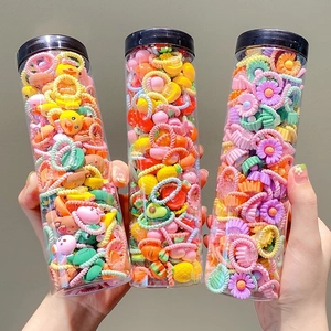 Three jars of colorful elastic hair ties for kids with cute flower and fruit shapes