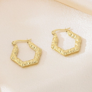 Détail de la texture ondulée irrégulière sur les boucles d'oreilles dorées en acier