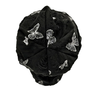 Detail shot of black distressed knit beanie with silver butterfly prints and ripped texture