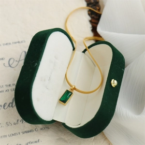 Detail of emerald rectangle pendant on gold snake chain with a velvet jewelry box
