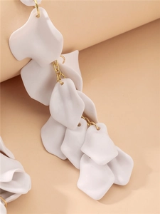Détails des boucles d'oreilles pétales de rose blancs et maillons dorés sur rose