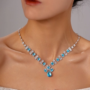 Detail of zircon bow necklace with blue water drop gems on model neck