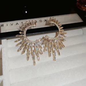 Golden sunburst C-shaped earrings with baguette zircons and sparkling radiant design