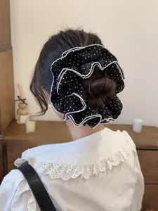 Detail of oversized black and white polka dot scrunchie with scalloped white edges