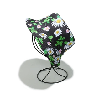 Détail d'un bob noir avec marguerites blanches et motif floral sur support métallique