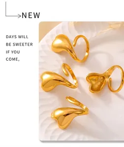 Detailed view of four irregular 18k gold plated liquid metal style open rings on ceramic