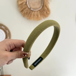 Détail du serre-tête éponge tricoté vert avec étiquette artisanale et texture sergé