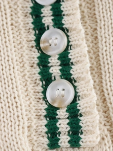 Macro shot of off-white and green striped knit fabric with pearlescent buttons