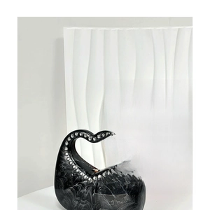 Macro detail of heart-shaped acrylic bag with black marble texture and rhinestone handle