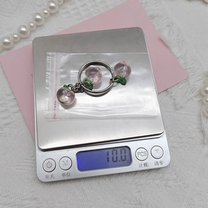 Detail shot of a pink peach keychain on a digital scale weighing approximately 10.0g