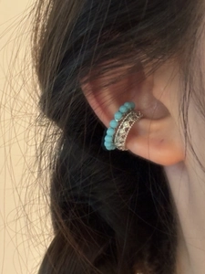 Gros plan sur l'oreille avec earcuff à perles bleues et design géométrique argenté