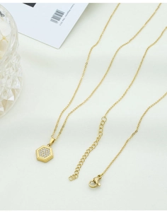 Macro view of gold hexagon honeycomb pendant with white cubic zirconia on thin chain