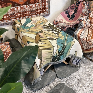 Macro view of woven cotton camping blanket showing tropical leaf patterns and fringe detail