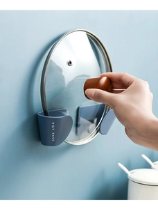 Detail showing wall-mounted dark blue plastic pot lid rack installation on a blue wall