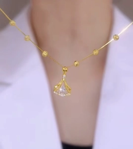 Macro view of gold pendant necklace with fan-shaped zircon and polished beads