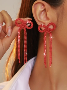 Detail of red bowknot earrings with sparkling rhinestones and long tassel on a model