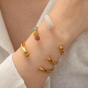 Golden open bracelets with rainbow crystals and white pearls on model wrist