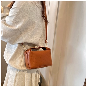 Detail of caramel leather crossbody bag featuring rich rabbit embossed pattern and gold clasp