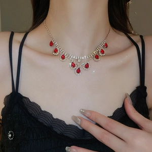 Detail of vintage necklace set with red teardrop gemstones on a model wearing black lace