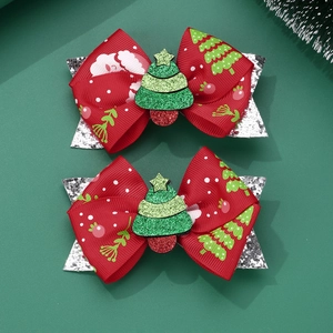 Close-up of handmade red Christmas hair bows with Santa patterns and green glitter trees