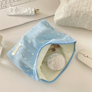 Gros plan d'une trousse à maquillage bleu clair en dentelle et paillettes sur bureau