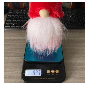 Detailed view of red plush Christmas gnome on a scale weighing approximately 99.3g