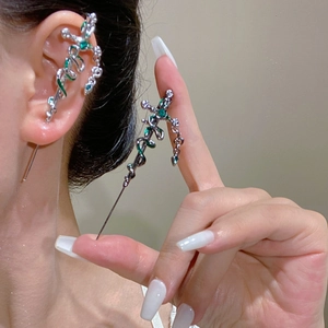 Detail of silver snake and sword ear cuff with dark green gemstones in a punk style