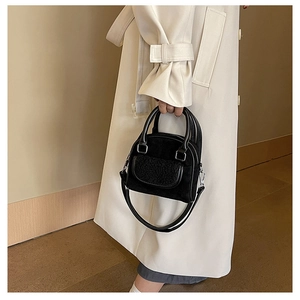 Detail of black plush patchwork tote with circular handles on a white winter coat