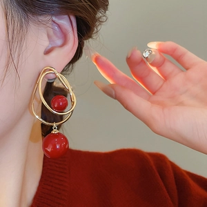 Gros plan de boucles d'oreilles dorées avec perles rouges portées par un mannequin