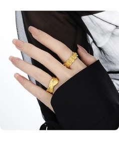 Close-up of golden wavy textured rings with small diamonds on a hand model