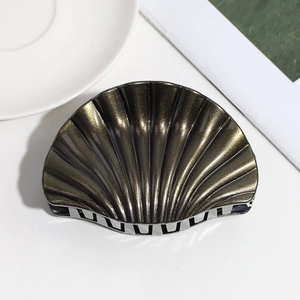 Macro shot of shell-shaped hair claw clip with dark bronze glitter finish and metal hinge