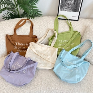 Detail of canvas tote bags in five pastel colors with adjustable straps and text print