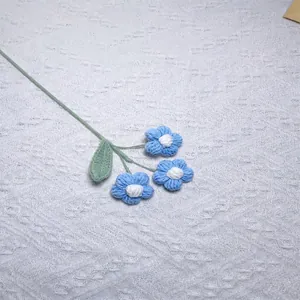 Close-up of handmade crochet puff flowers in sky blue with white core and green leaf