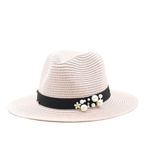 Detailed view of women's straw hat featuring black ribbon with pearls and flower accent