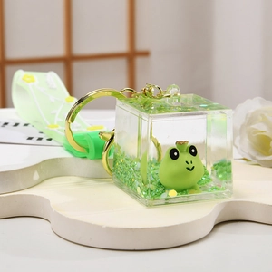 Detail of green frog liquid keychain with acrylic square, glitter and floral strap