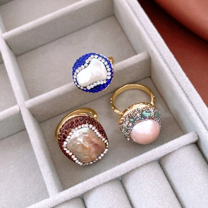 Macro detail of three 18k gold vintage rings with baroque pearls and colorful zircons
