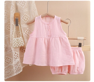 Detail of pink cotton muslin baby girl sleepwear set featuring button-up top and bloomers