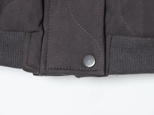 Detailed close-up of twill fabric jacket hem with ribbed cuff and metal snap button